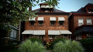 A brick building with a central entrance, large windows with awnings, and a pathway leading to the entrance. - Beautiful 2BR Apt. /Pittsburgh/East/Regent Square/Frick Park (Pittsburgh)