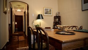 A dining area with a wooden table, chairs, a lamp, a framed picture, and a bookshelf. - Beautiful 2BR Apt. /Pittsburgh/East/Regent Square/Frick Park (Pittsburgh)