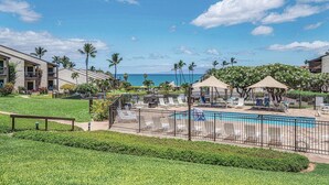 Ein Poolbereich eines Resorts mit Liegestühlen und Blick auf den Ozean.