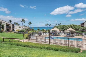 A resort pool area with lounge chairs, a pool, and a view of the ocean. - Hale Kamaole 150 | Ground-Floor Ocean View, Lanai, King Bed, Split A/C, Sleeps 4 (Kihei)
