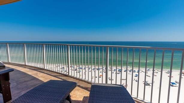 A balcony with a view of a beach with umbrellas and people. - Stylish Oceanview Escape 3 BR 3 BA Phoenix Orange Beach 902 (Orange Beach)