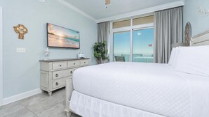 A bedroom with a large bed, a dresser, a painting, a plant, and a balcony with curtains. - Stylish Oceanview Escape 3 BR 3 BA Phoenix Orange Beach 902 (Orange Beach)