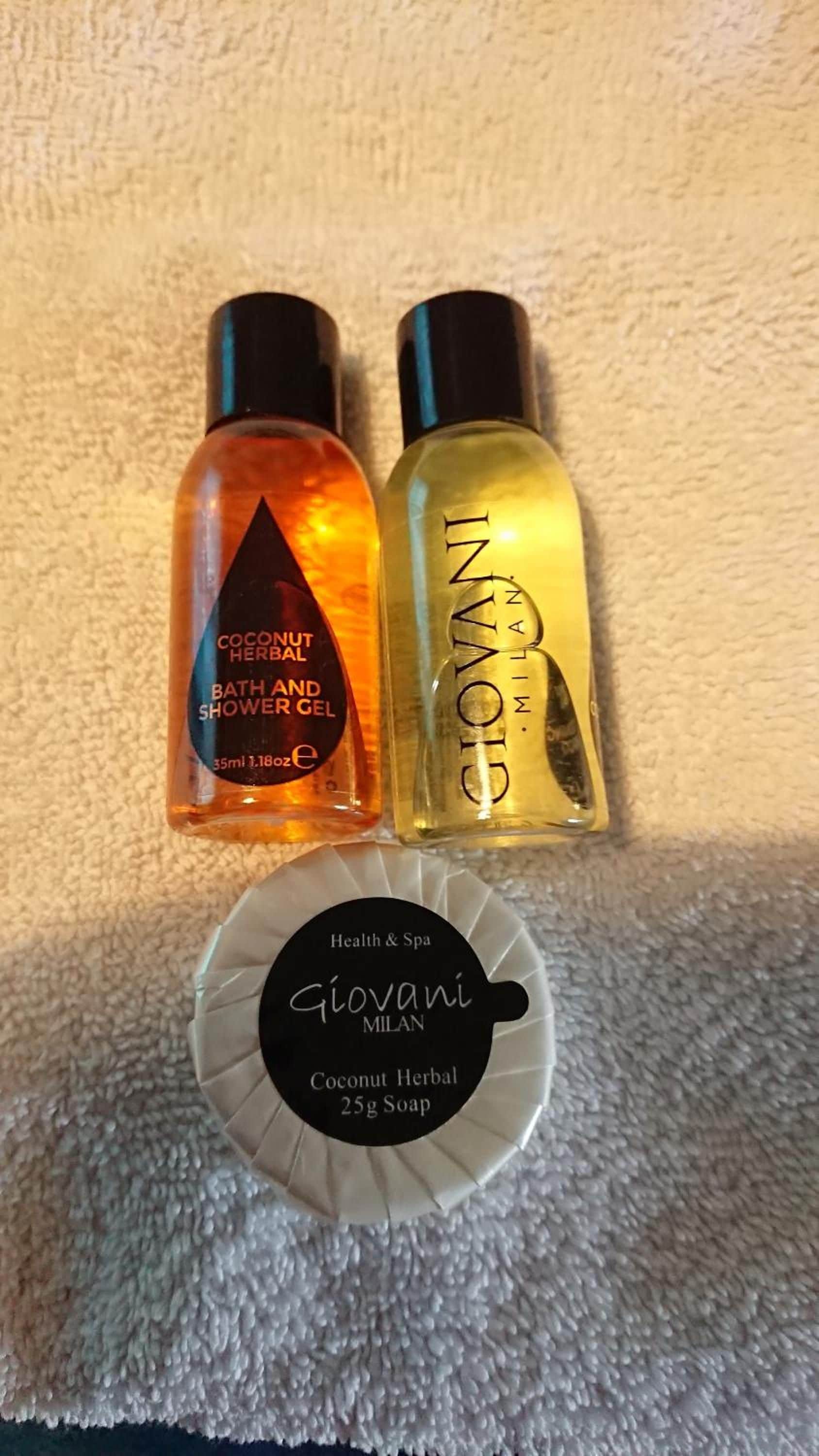 Two bottles of bath products and a soap bar on a textured surface.