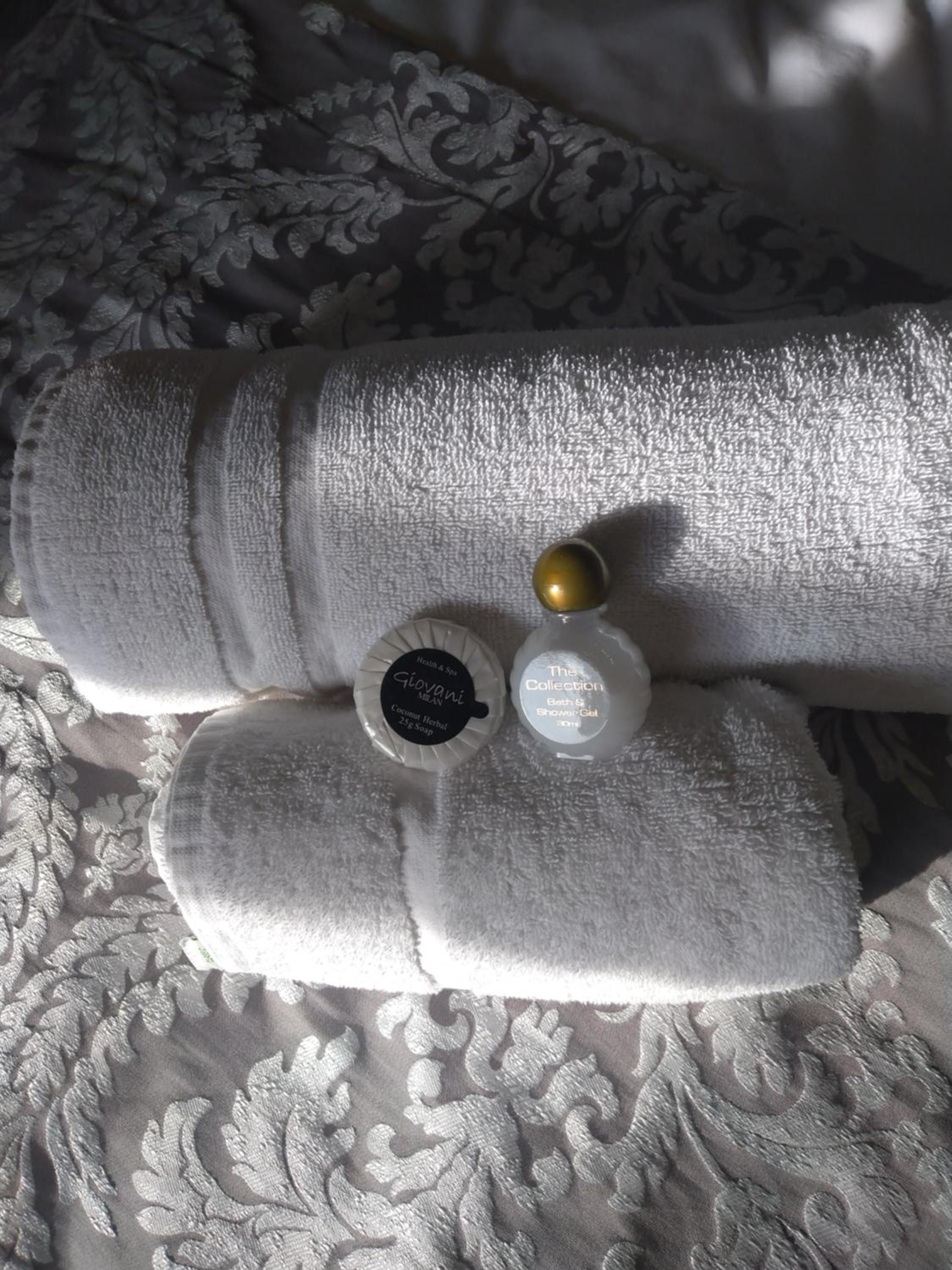 A neatly folded towel and two toiletry bottles on a textured fabric surface.