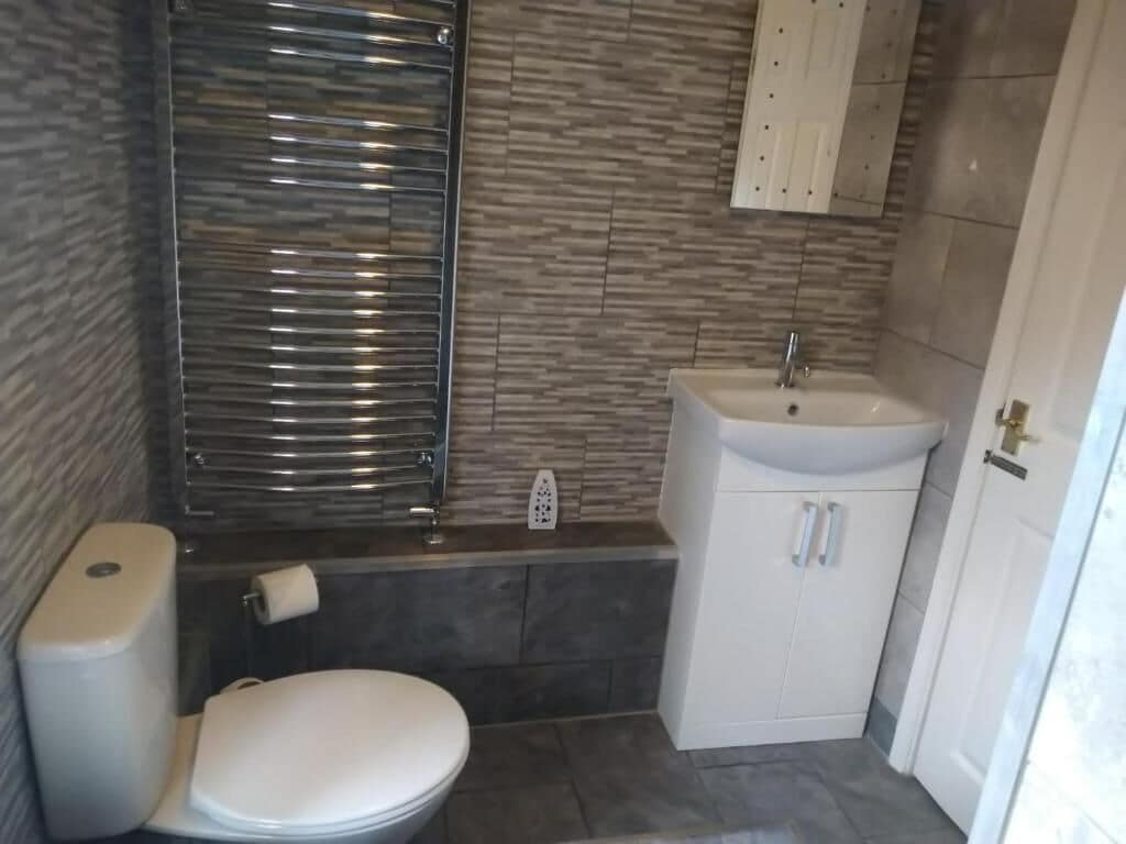 Un baño con inodoro, lavamanos y zona de ducha.
