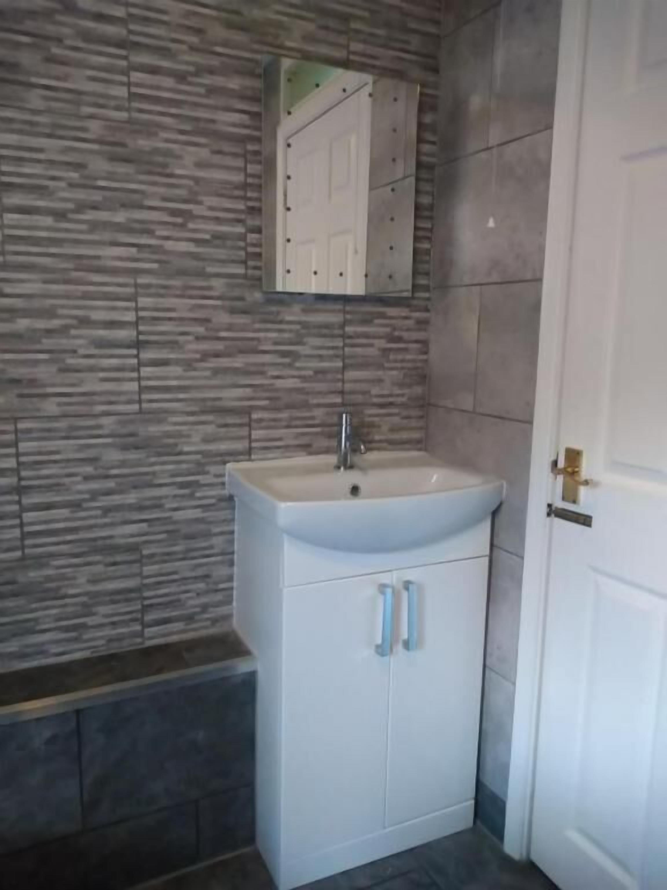 A bathroom with a white sink, a mirror, and a door.