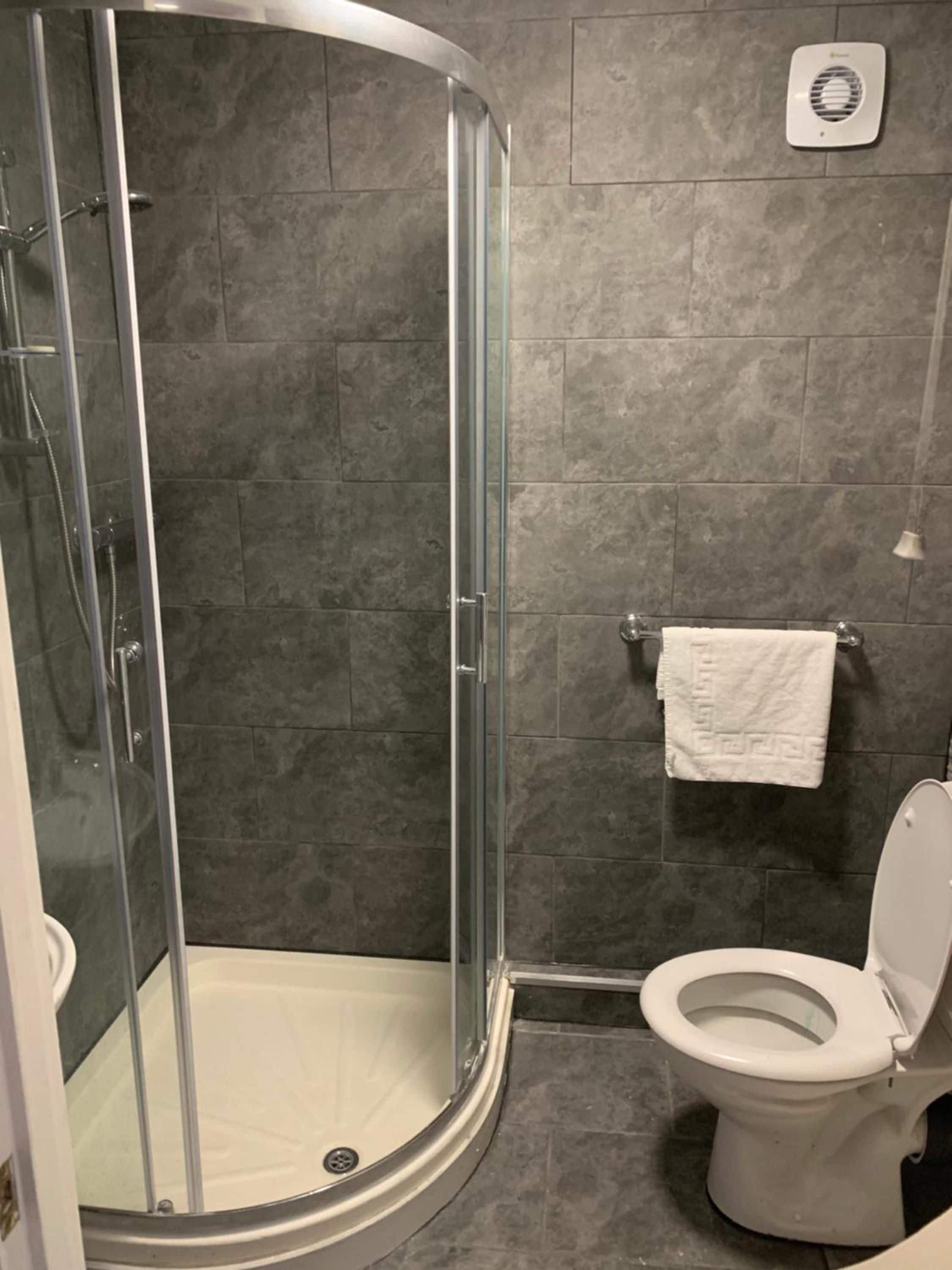 A bathroom with a glass-enclosed shower, a white toilet, and a towel rack.