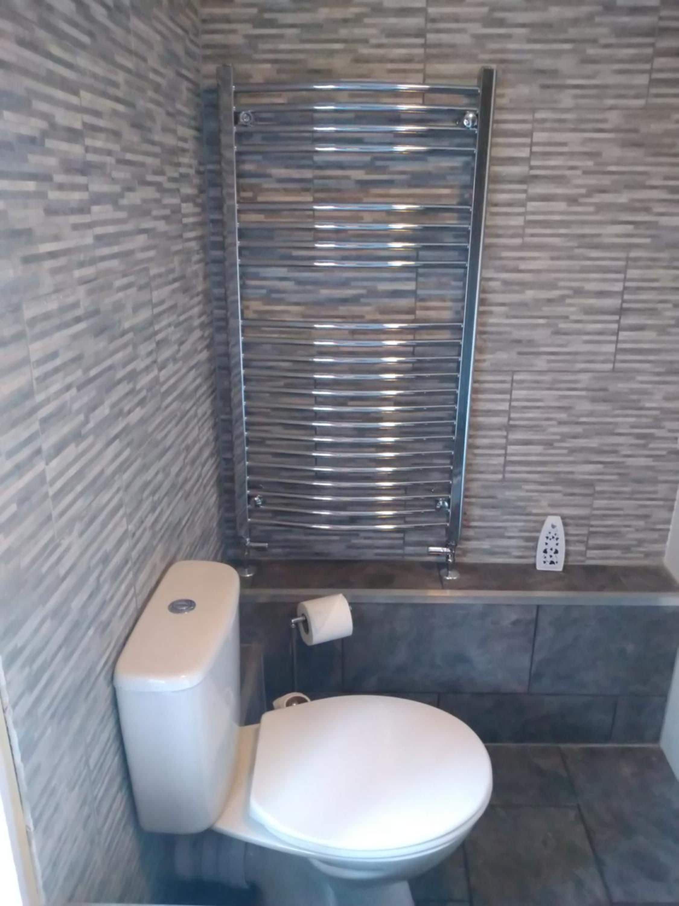 Un baño con un inodoro, un secador de manos y un perchero para toallas.