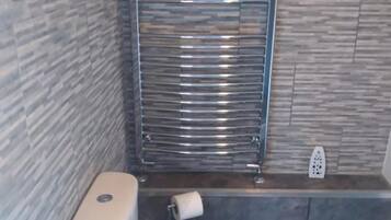 Un baño con un inodoro, un secador de manos y un perchero para toallas.