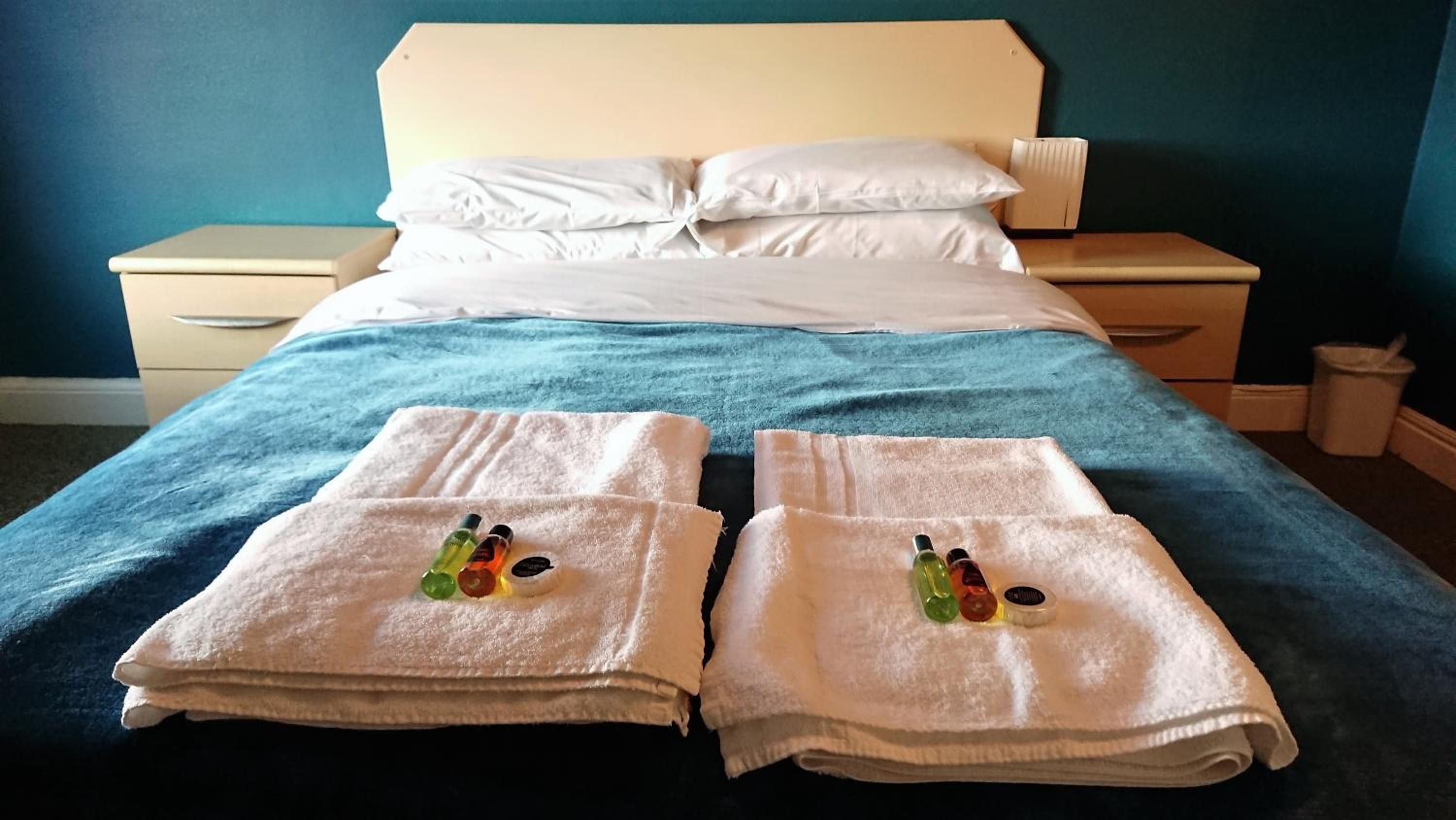 Una habitación de hotel con una cama, dos mesitas de noche y una pared azul.