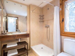 A bathroom with a wooden vanity, a bathtub, and a shower area.