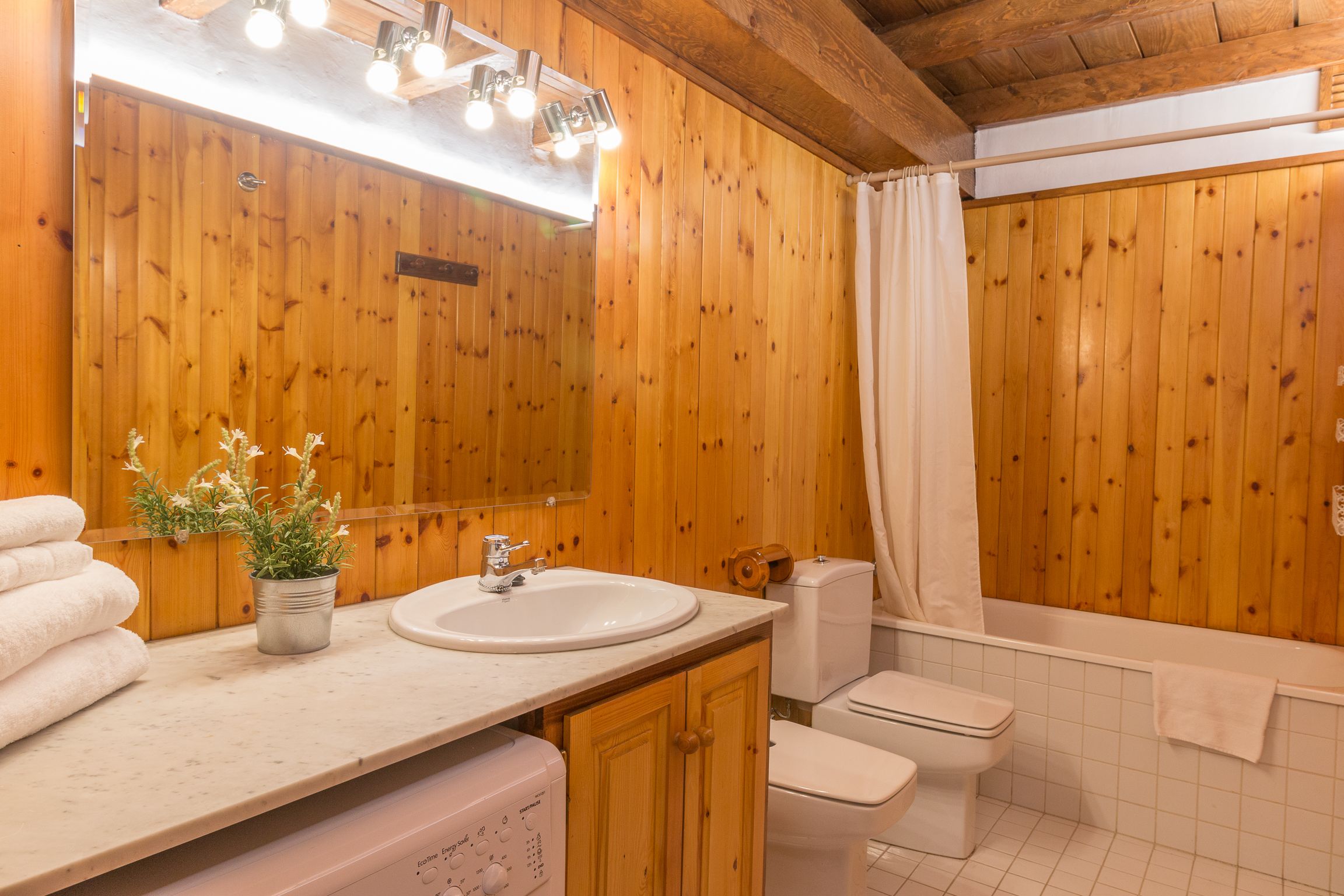 Un baño con paneles de madera, un lavabo, un inodoro y una bañera.