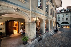 A historic hotel with a grand entrance, outdoor seating, and cobblestone streets. - Hotel Stadthaus (Burgdorf)