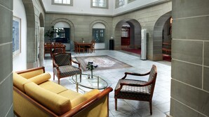 A spacious lobby with a high ceiling, large windows, and a central seating area with sofas and chairs. - Hotel Stadthaus (Burgdorf)