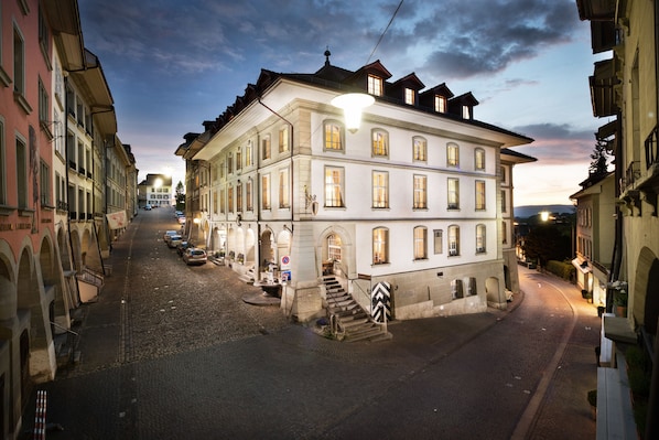 A historic building with a prominent staircase and a well-lit entrance.