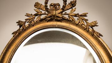 A mirror with an ornate gold frame featuring leaf and flower motifs.