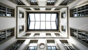 A high-ceiling atrium with large windows and multiple smaller windows, providing natural light to the space. - Hotel Stadthaus (Burgdorf)