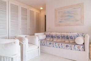 Una stanza con un divano bianco, una poltrona bianca e un grande quadro appeso al muro.
