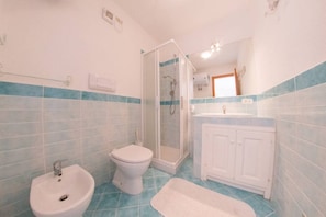 Ein Badezimmer mit Dusche, Toilette, Bidet und Waschbecken.