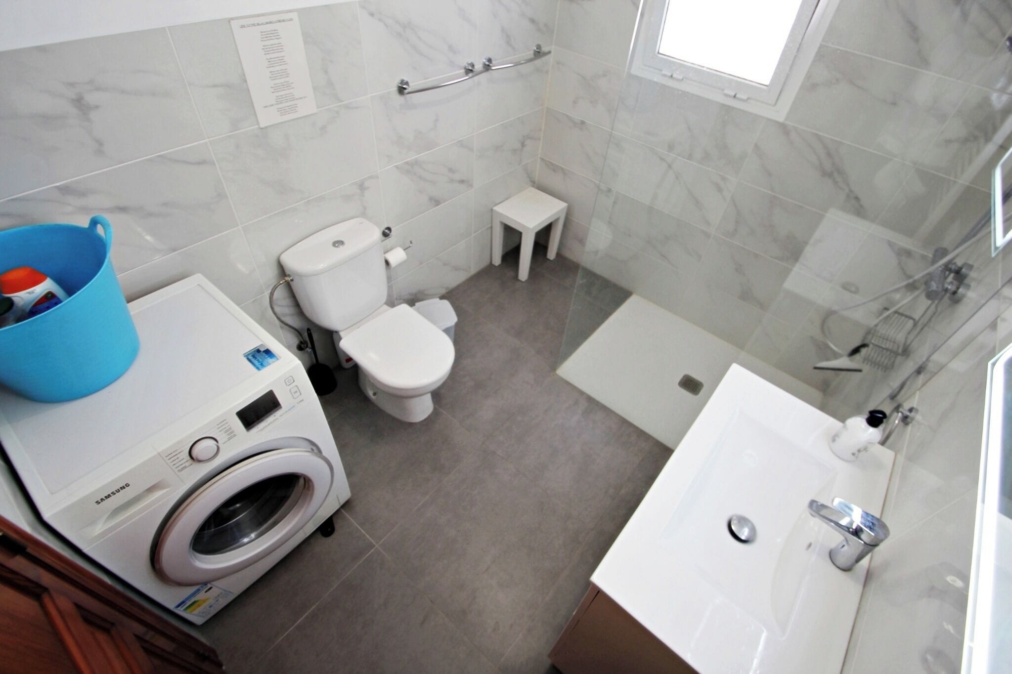 A modern bathroom with a washing machine, toilet, and bathtub.