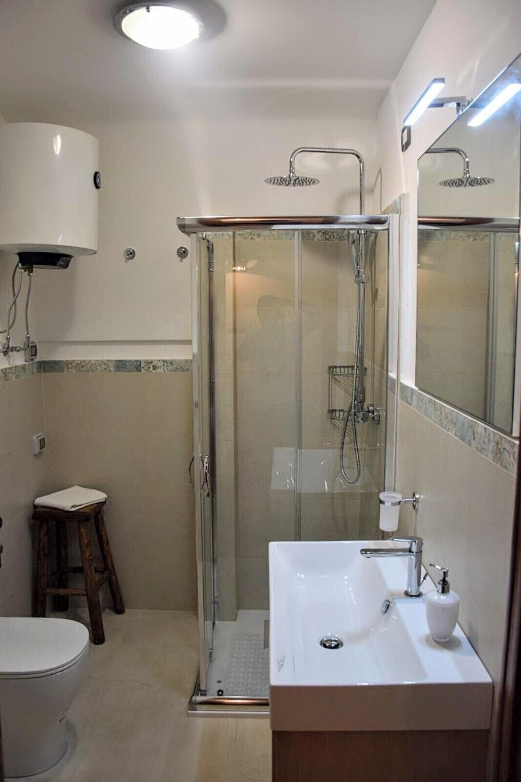 A bathroom with a glass-enclosed shower, a white sink, a toilet, and a mirror.