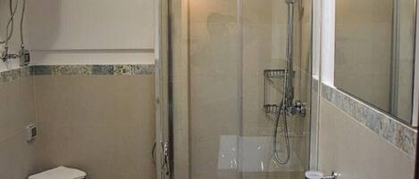 A bathroom with a glass-enclosed shower, a white sink, a toilet, and a mirror.