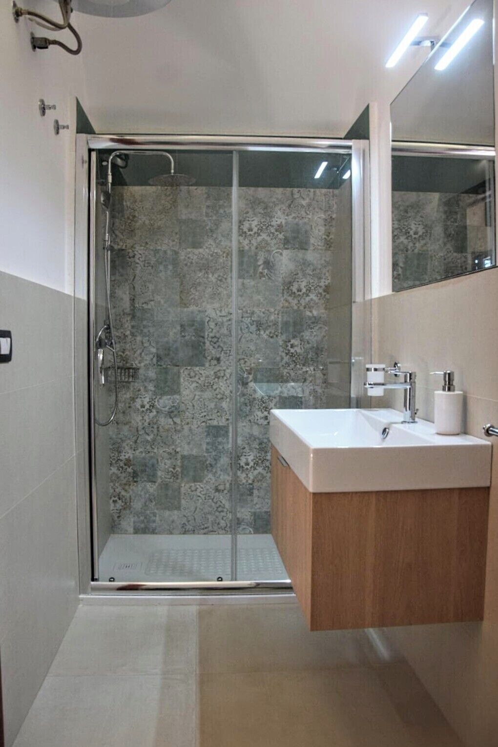 Une salle de bain avec une douche à parois de verre, un meuble-lavabo en bois et un miroir.