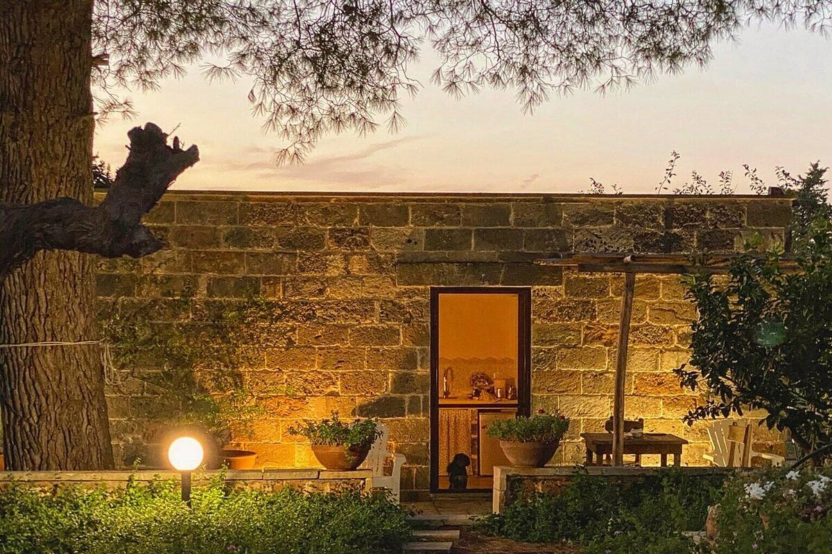 Un bâtiment en pierre avec un jardin et un chemin qui mène à une porte.