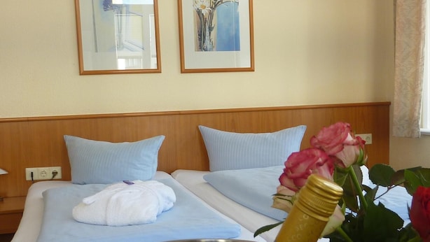 Ein Hotelzimmer mit zwei Betten, einem Metalleimer und einer Champagnerflasche.