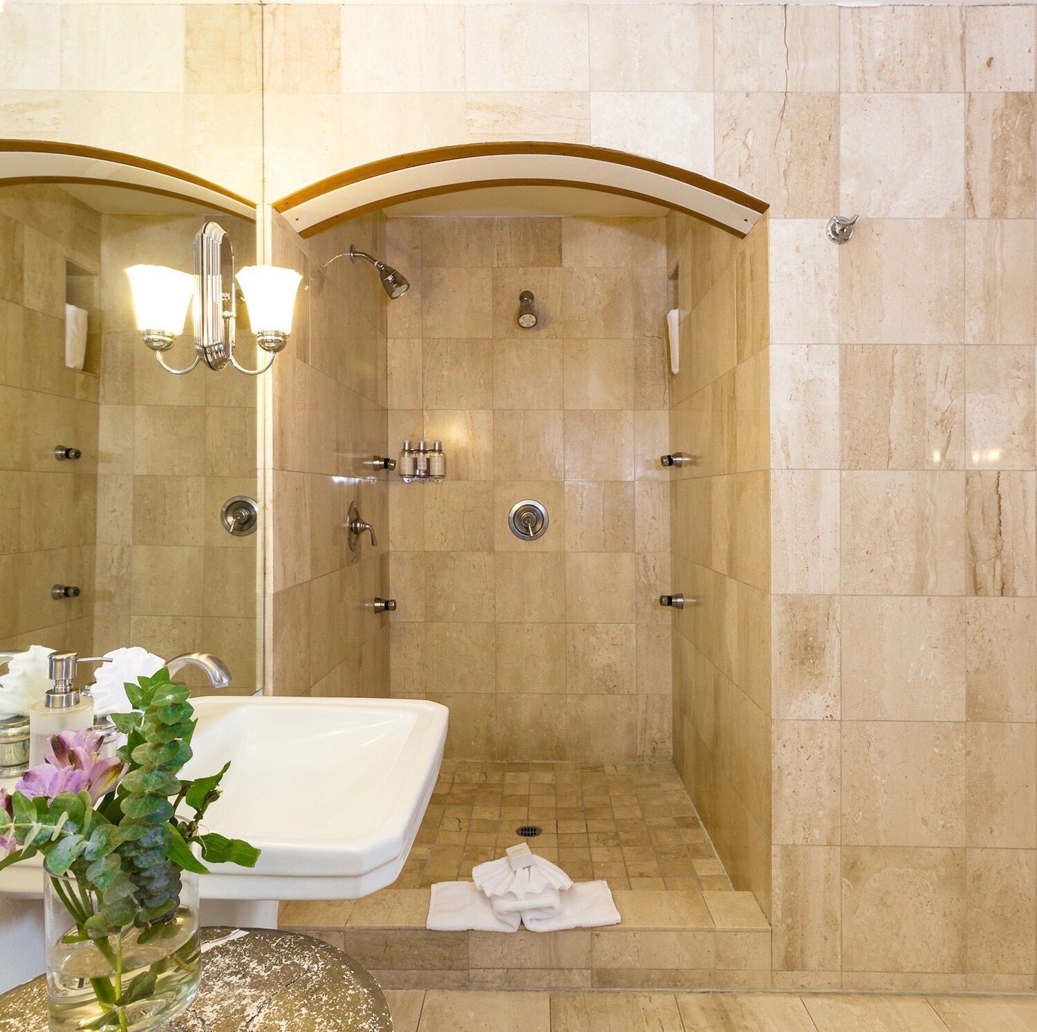 Un baño moderno con una ducha amplia, un lavabo y un espejo.