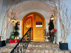 A wooden door with a decorative arch, a staircase leading up to it, and a bicycle parked to the right. - Abendblume - Adults Only (Leavenworth)