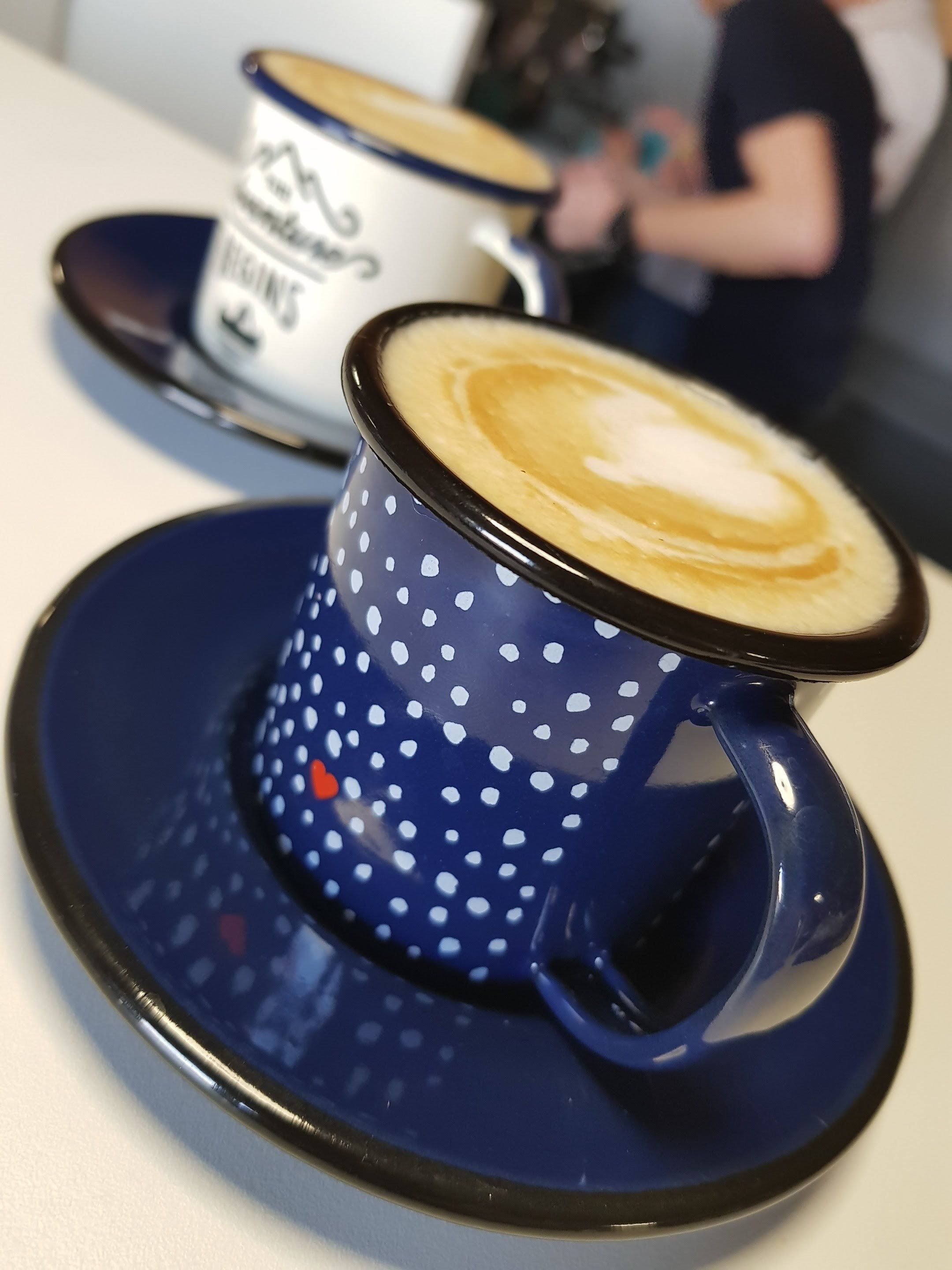 Una taza azul con lunares blancos y un platito sobre una mesa.