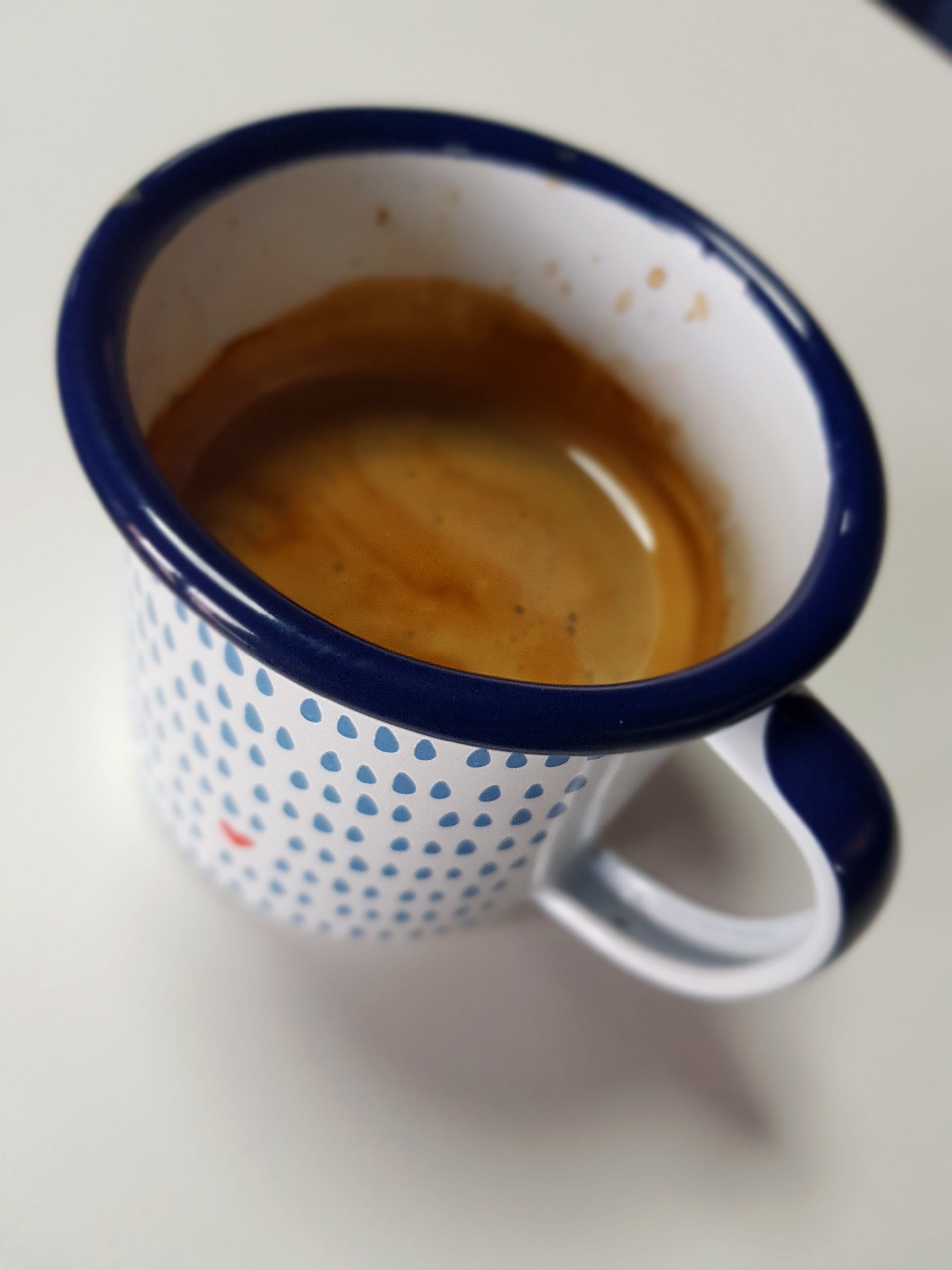 Primer plano de una taza de cerámica con borde azul y parte interior blanca con lunares azules.