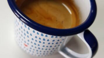 Primer plano de una taza de cerámica con borde azul y parte interior blanca con lunares azules.