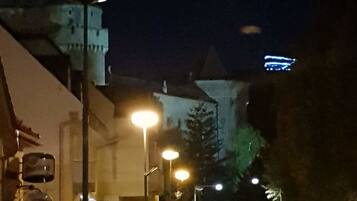 A nighttime street view with a tower in the background, street lamps, and buildings along the road.