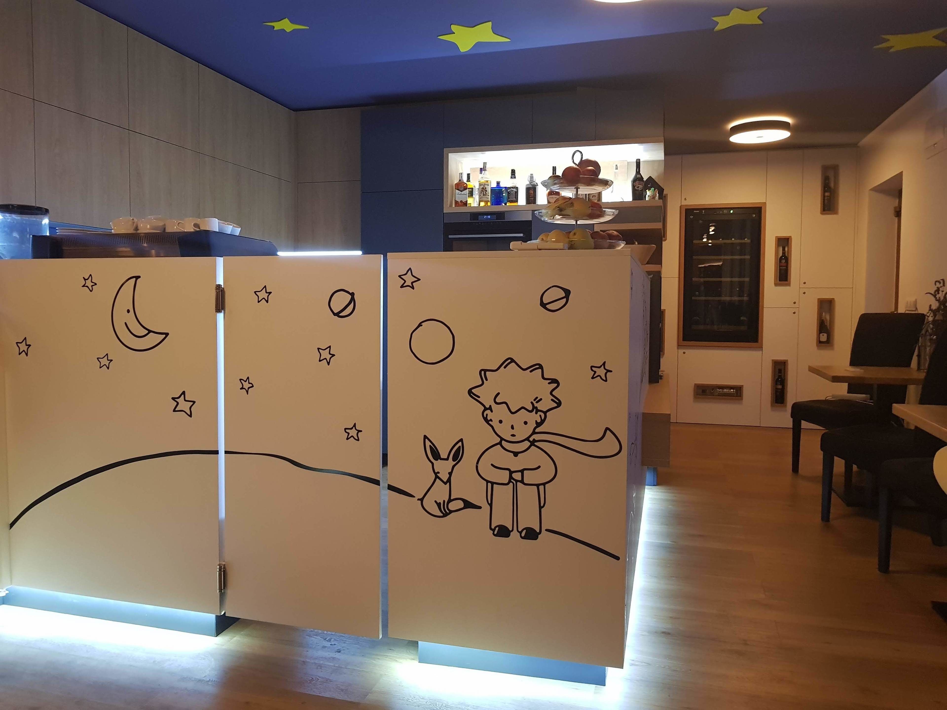 Ein Zimmer mit Holzboden, einer Theke mit Lebensmitteln und einer Wand mit einem Himmels-Design.
