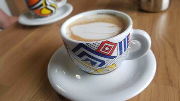 A cup of coffee on a saucer with a colorful geometric pattern.