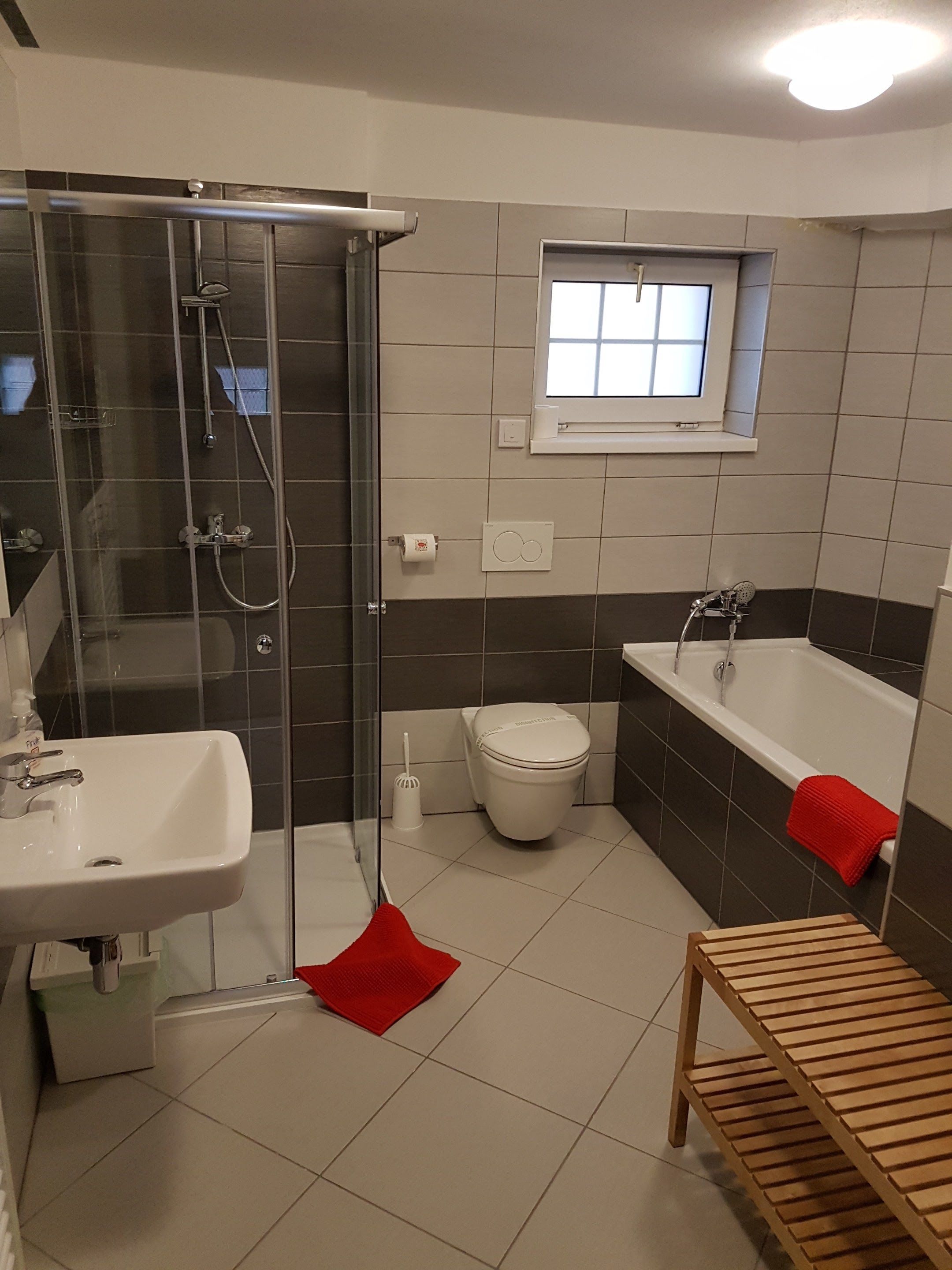 Ett badrum med en dusch som är avskärmad med glasväggar, ett vitt handfat, en toalett och ett badkar.