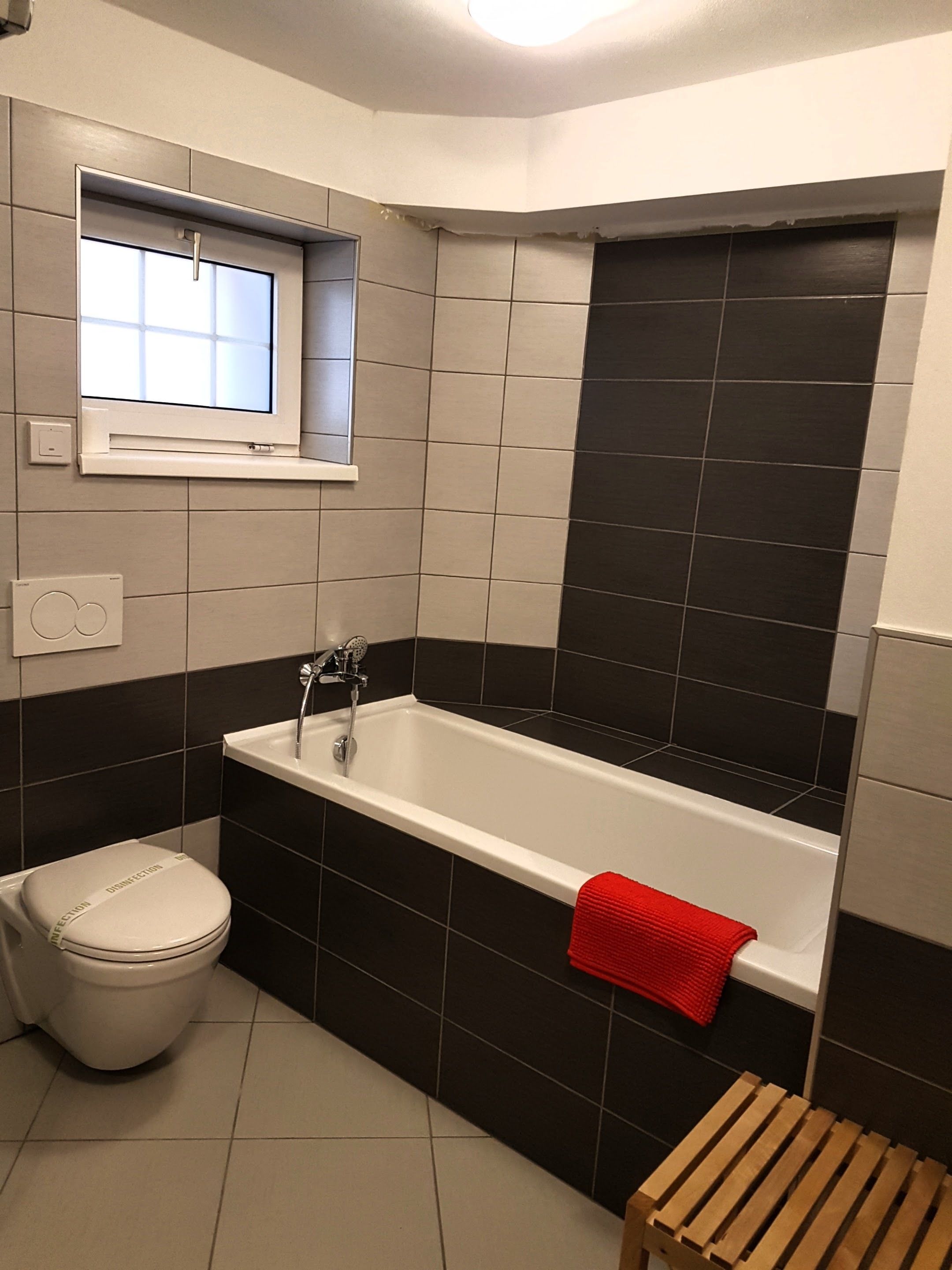Un baño moderno con bañera, inodoro y ventana sobre el lavabo.