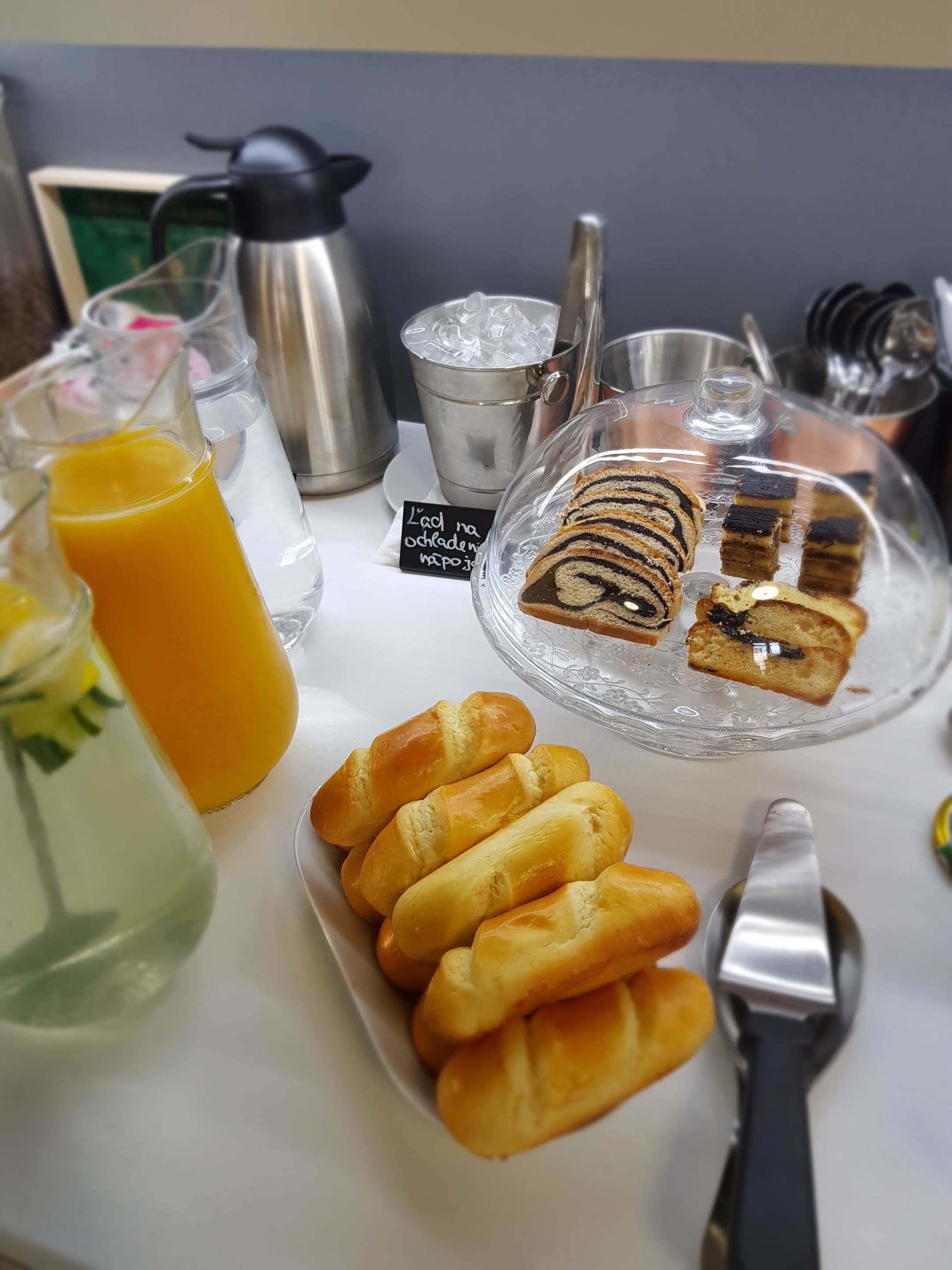 A breakfast setting with pastries, a glass of orange juice, and a coffee pot.