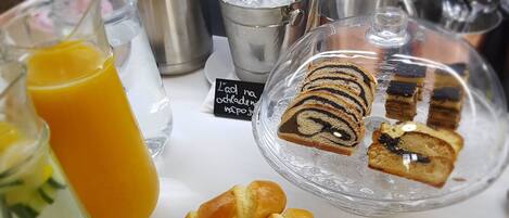 A breakfast setting with pastries, a glass of orange juice, and a coffee pot.