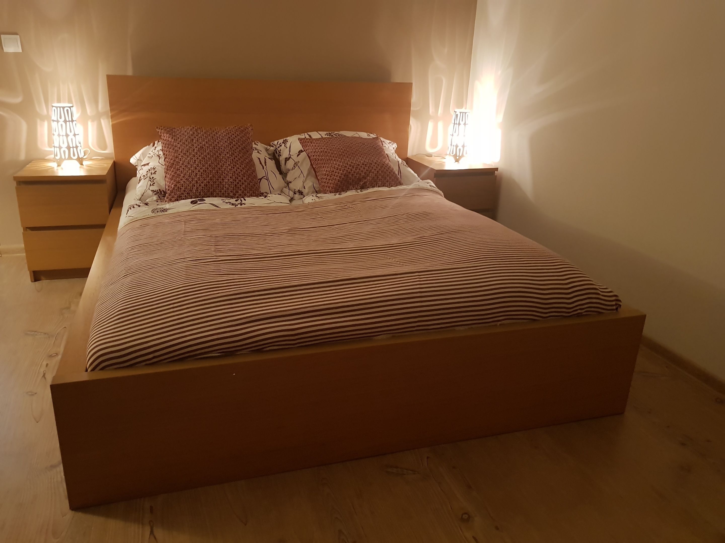 Ein Einzelbett mit gestreifter Bettdecke, zwei Kissen und zwei Nachttischlampen.