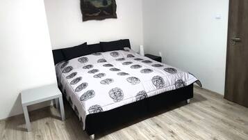 Ein Schlafzimmer mit einem Bett, einem Nachttisch, einem Wandbild und einer Holztür.