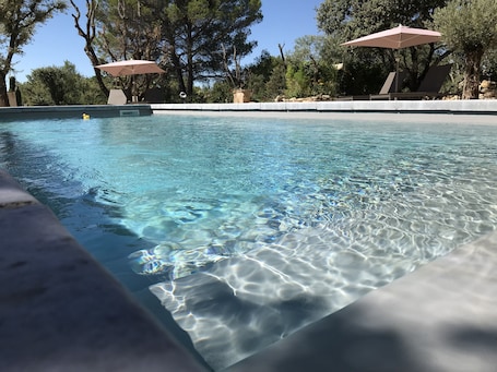 Una piscina al aire libre de temporada, sombrillas