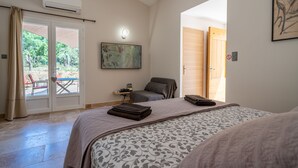 Un dormitorio con cama, escritorio y silla. Hay una ventana con cortinas, un cuadro en la pared y un equipo de aire acondicionado.