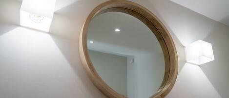 A round mirror with a wooden frame mounted on a white wall.