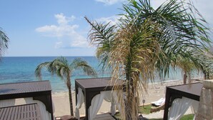 A beachside resort with wooden cabanas, palm trees, and a view of the ocean. - Coralli Apartments (Rhodes)