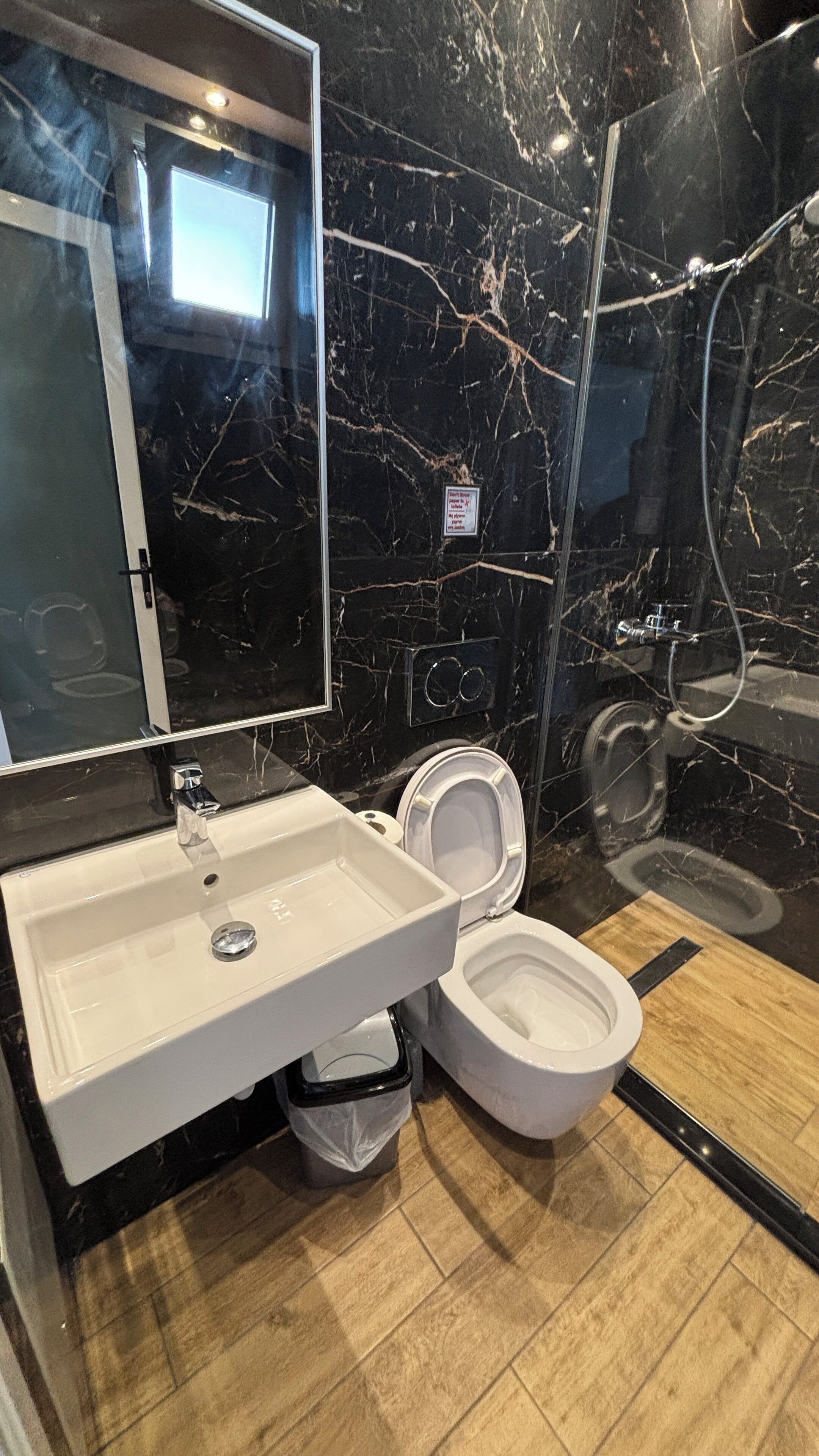 Ein Badezimmer mit Marmorwand, Waschbecken, Toilette und Dusche.
