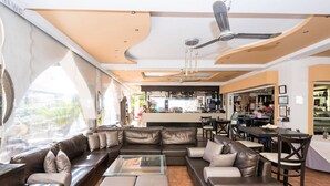 A modern lounge area with leather sofas, a glass coffee table, and a bar in the background. - Coralli Apartments (Rhodes)