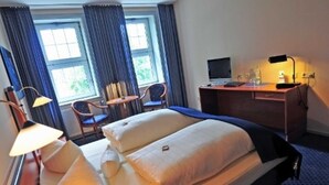 Une chambre d’hôtel avec deux lits, un bureau, une chaise, une lampe et un téléviseur.
